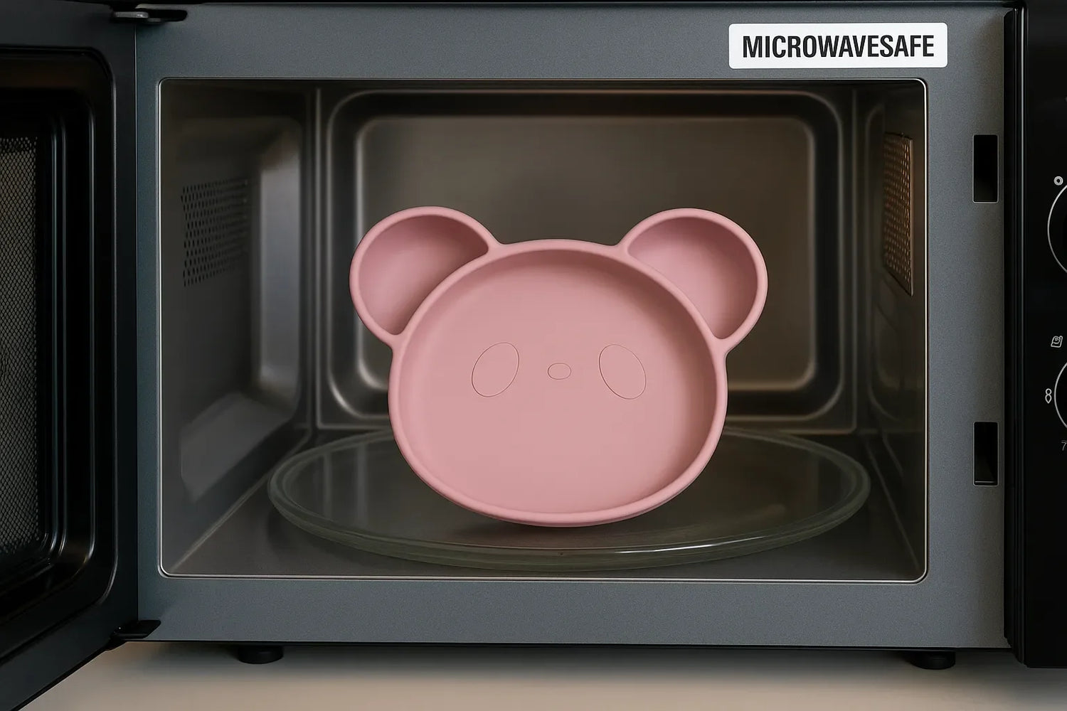 Assiette bébé en silicone rose en forme d’ours placée dans un micro-ondes, certifiée micro-ondes safe avec intérieur en inox.