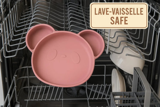 Assiette bébé en silicone rose posée dans un lave-vaisselle ouvert, avec étiquette “Lave-vaisselle safe” sur fond inox et vaisselle propre.