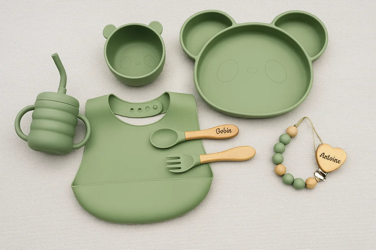 Set repas bébé complet vert sauge avec assiette, bol, tasse, couverts personnalisés, bavoir souple et attache-tétine en bois.