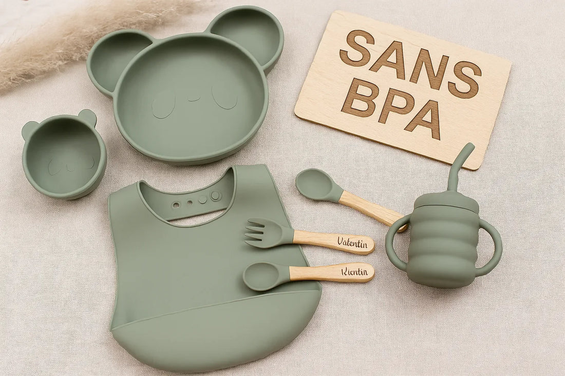 Vaisselle bébé sans BPA : assiette panda, bol, tasse, couverts gravés et bavoir en silicone vert sur fond beige avec panneau “SANS BPA”.
