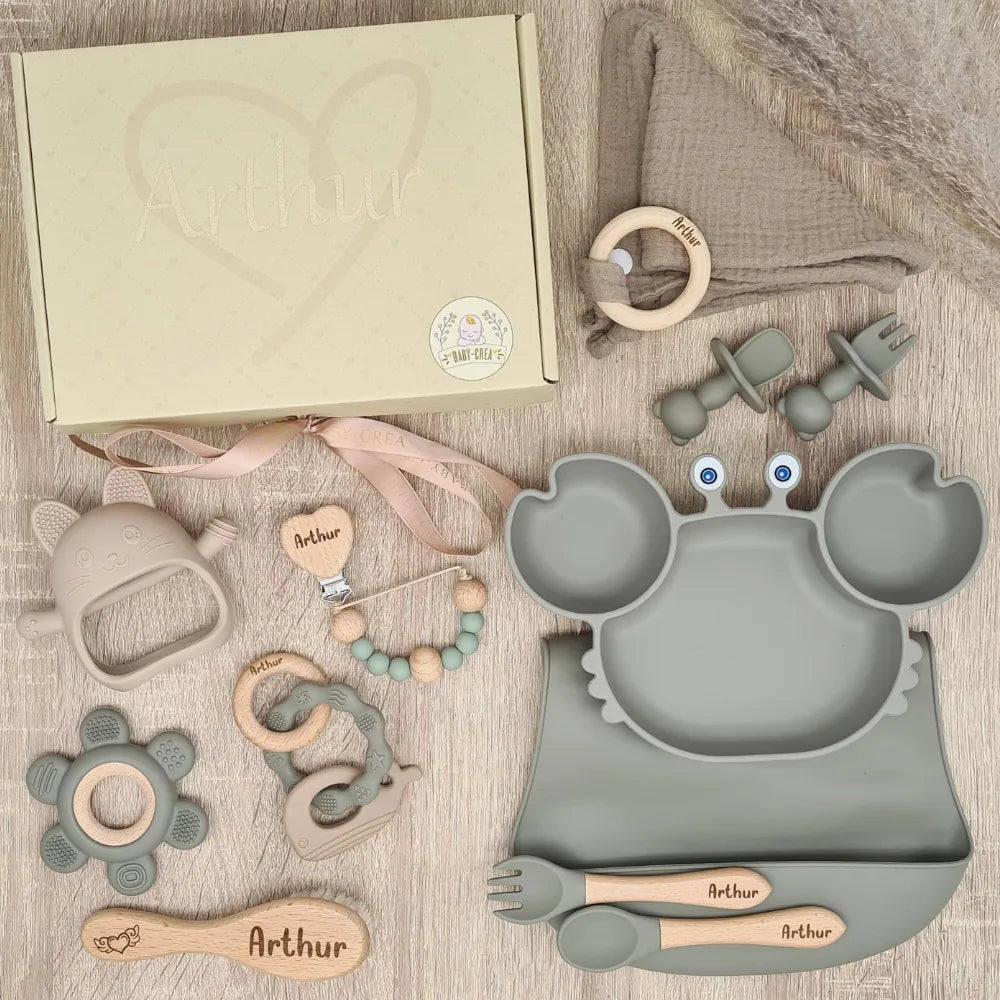 Coffret naissance complet 10 pièces personnalisé pour Arthur, coloris vert olive, avec couverts gravés, brosse en bois et anneau de dentition dauphin.
