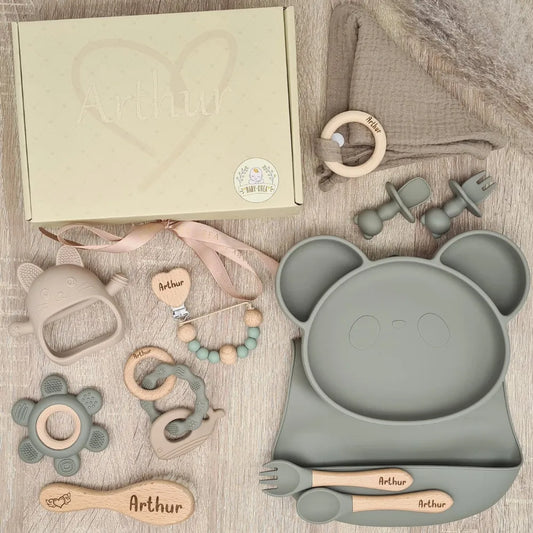 Coffret de naissance avec un plateau en forme de panda et divers accessoires pour bébé, tous en couleur grise, personnalisés avec le nom Arthur.