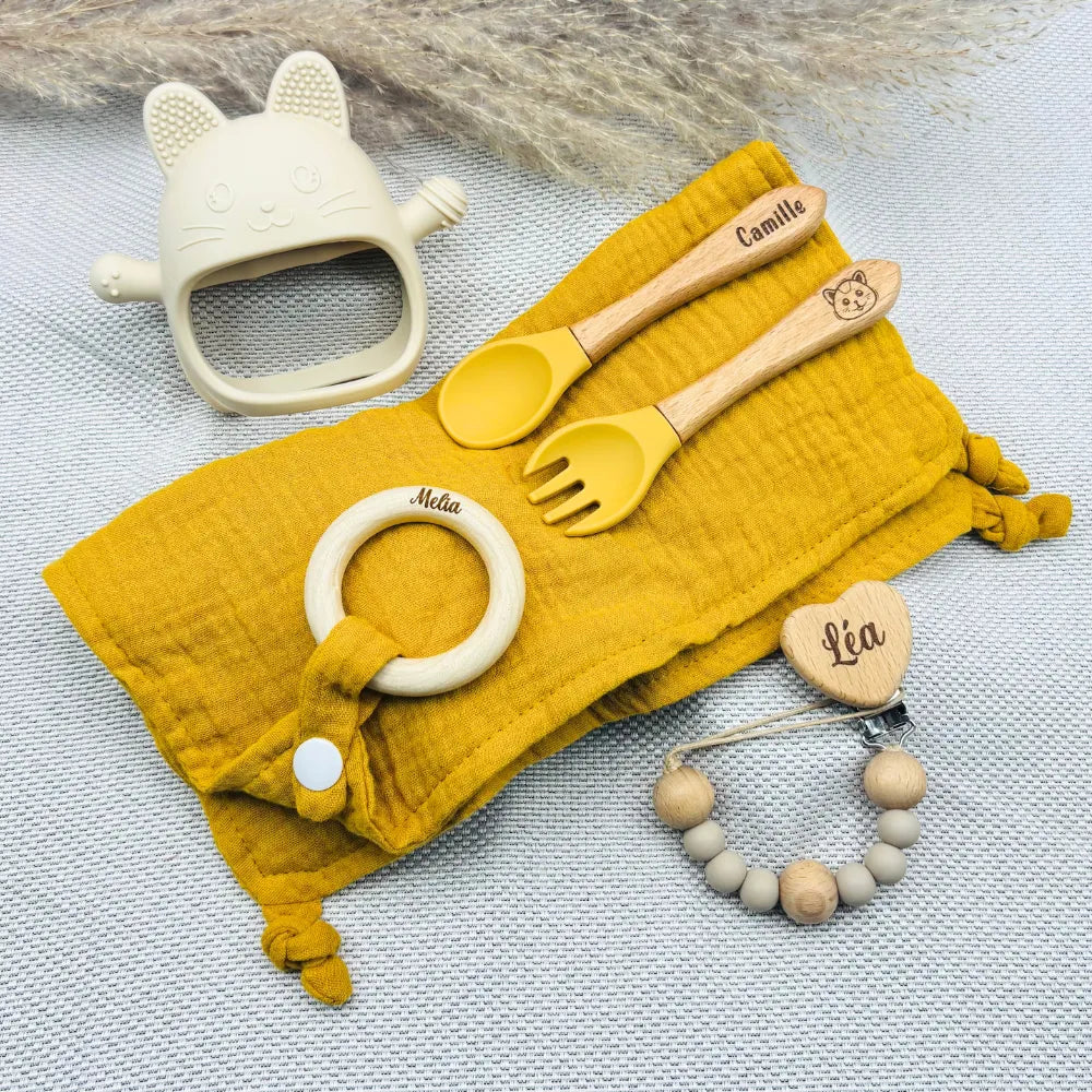 Ensemble repas bébé moutarde avec lange, couverts gravés Camille, attache tétine prénom Léa, anneau de dentition prénom Melia, jouet de dentition chat crème – coffret naissance personnalisé tendance.