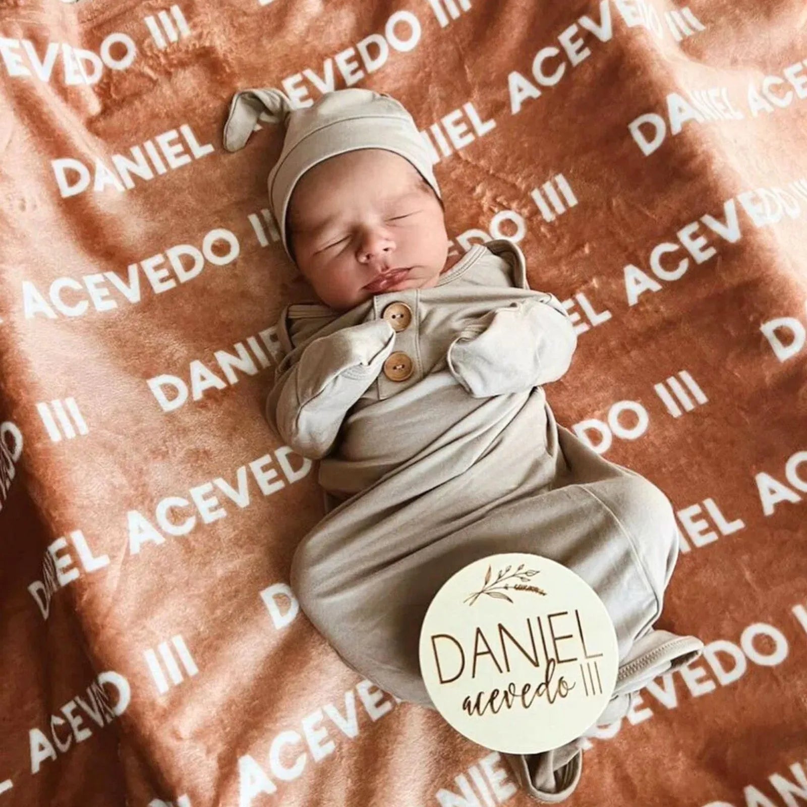Nouveau-né dormant sur une couverture personnalisée couleur terracotta (rouille) avec prénom Daniel. Tissu doux idéal pour la peau de bébé et photo naissance.