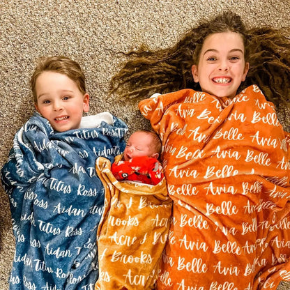 Frères et sœurs allongés avec leurs couvertures personnalisées : plaid bleu prénom Titus et plaid orange prénom Belle. Cadeau idéal pour toute la famille.